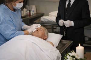 Professionnel funéraire réalisant une toilette mortuaire sur un défunt allongé en chambre funéraire