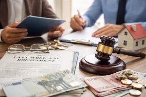 Personnes signant des documents de succession sur une table avec un maillet de juge, une maquette de maison et des billets en euros